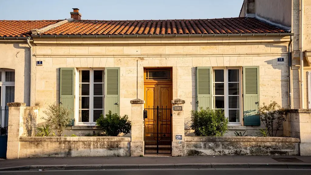 Façade d'une échoppe bordelaise typique en pierre calcaire à Caudéran avec jardin devant et volets traditionnels